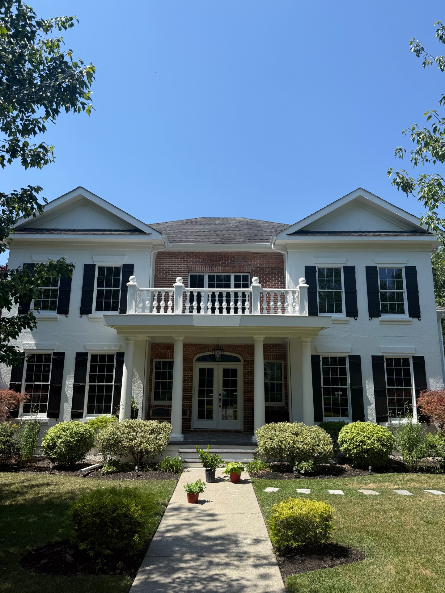 Freshly painted stucco home exterior with black shutters — after